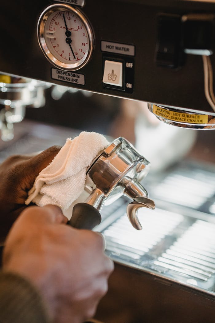 Close-up of a barista cleaning a portafilter on a coffee machine, ensuring hygiene.